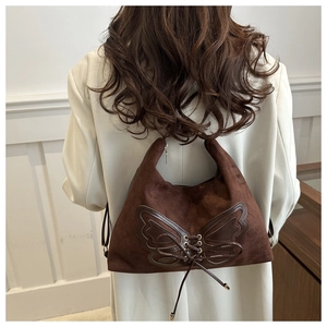 Detail der dunkelbraunen Wildleder-Tote mit Schmetterlingsaufnäher und Kordelzug-Design