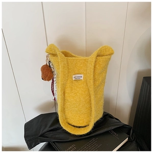 Detail of yellow plush bucket bag with LOVE FASHION label and small brown bear charm