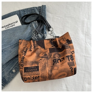 Close-up of newspaper print pattern and chain leather strap on a brown tote bag