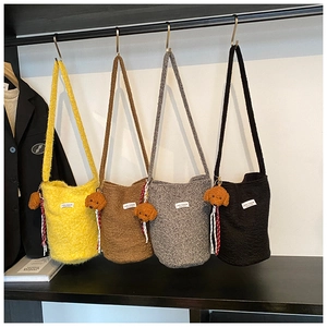 Detail of wool bucket bags in four colors with teddy bear charms and logo patch