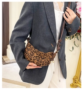 Detail of leopard print crescent bag with brown knotted leather strap and gold hardware