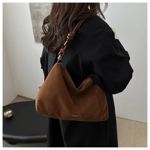 Detail of dark brown suede tote bag with knotted strap and silver metal hardware