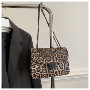 Detail of leopard print crossbody bag with geometric buckle and chain strap on hanger