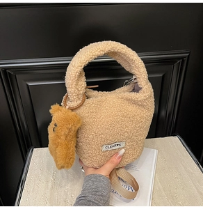 Close-up of beige fuzzy plush bucket bag featuring soft texture and brown bear pendant