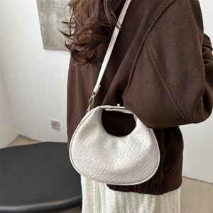 White woven texture hobo bag worn crossbody by a model in a stylish winter outfit