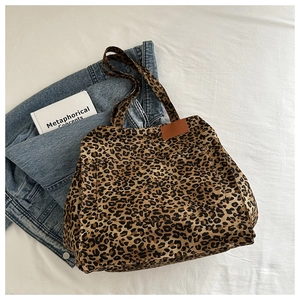 Detailed top view of leopard print canvas tote bag with leather tag on denim jacket