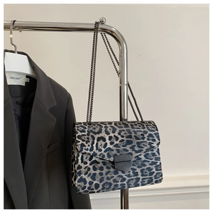 Close-up of leopard print crossbody bag with metallic chain strap and geometric clasp