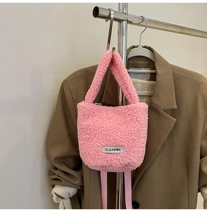Detailed view of pink plush crossbody bucket bag with white brand label on metal hanger