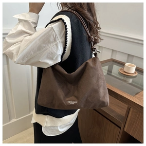 Close-up of brown suede hobo bag with vintage leather logo label and shoulder strap
