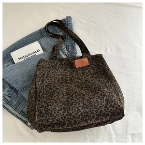 Detail view of leopard print tote bag with large pocket and leather patch on canvas