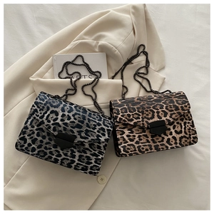 Detail of leopard print crossbody bag with metal buckle and chain on a beige blazer