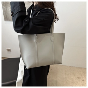 Minimalist light grey leather tote bag styled with a white skirt and a black jacket