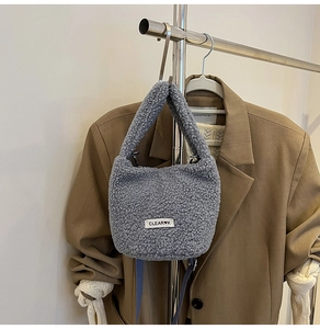 Plush lamb wool bucket bag with CLEAR logo shown on a minimalist neutral outfit display