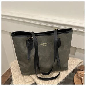 Macro di una borsa tote grigia con manici in pelle nera su una morbida coperta beige