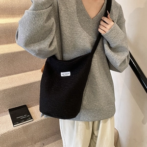 Large black fuzzy wool bucket bag with white logo label and comfortable wide shoulder strap