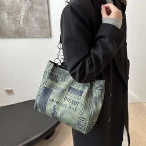 Retro newspaper print tote bag with silver chain strap shown on model in minimalist setting