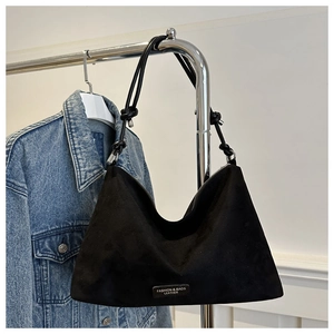 Detail of black suede hobo bag featuring knotted shoulder strap and silver metal hardware