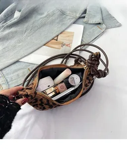 Close-up of leopard print crossbody bag showing spacious interior with makeup items