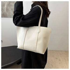 Detail view of a minimalist cream tote bag showing soft leather texture and large capacity