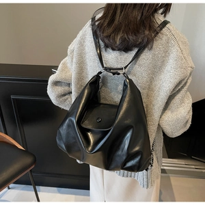 Close-up of black PU leather shoulder bag featuring accordion pleats and flap closure