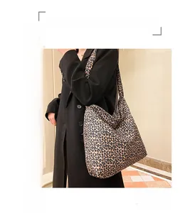 Detailed view of a large leopard print canvas tote bag worn across the shoulder