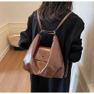 Detailed close-up of brown vintage faux leather backpack showing unique triangular silhouette