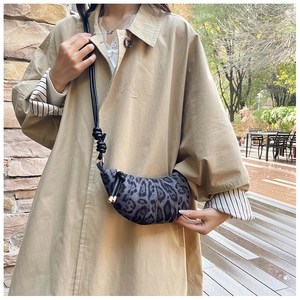 Detailed view of leopard print croissant bag with pleated design and knot strap details