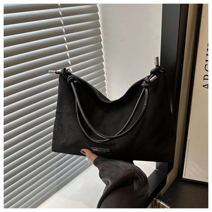 Detail of black suede hobo bag featuring metal hardware and leather brand tag