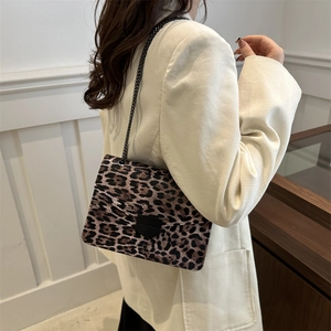 Leopard print shoulder bag with metal chain strap worn on a beige corduroy blazer