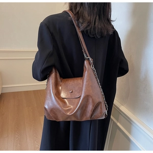 Detail of vintage brown leather hobo bag showing texture and metal chain strap