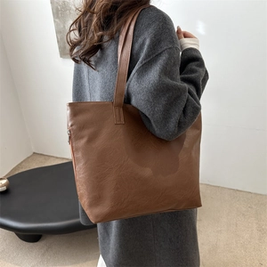 Minimalist large brown leather tote bag for women shown with grey winter coat
