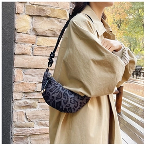 Detail of crescent leopard print bag featuring knotted rope shoulder strap and zip closure