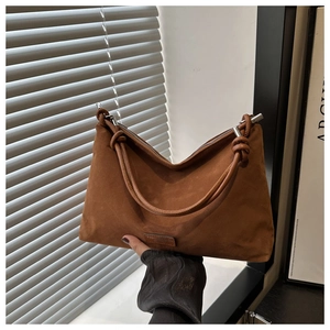 Detail of a brown suede tote bag featuring a creative knotted handle and zip closure
