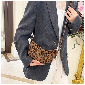 Detailed view of leopard print crescent bag on model with soft indoor lighting