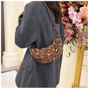 Detailed view of leopard print crescent bag with leather knotted strap on model shoulder