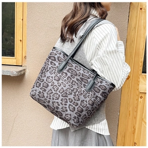 Detailed side view of leopard print tote bag with black leather straps on a model