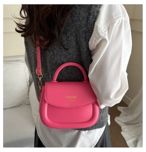 Detailed macro view of the bright pink mini crossbody bag with gold text and fine texture