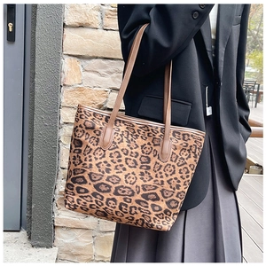 Detail of a large leopard print tote bag with brown straps and spacious interior
