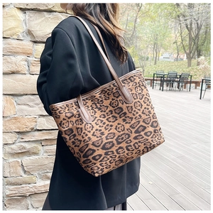Detail of leopard print tote bag featuring brown leather straps and spacious interior