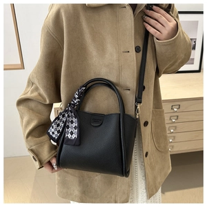 Detail of black lychee leather bucket bag with a stylish checkered silk scarf accent