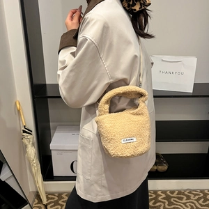 Chic beige faux shearling bucket bag worn by model, soft plush texture with crossbody strap