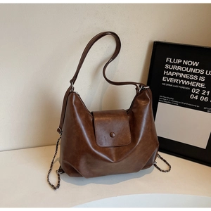 Detail of vintage brown PU leather tote with metal chain and buckle closure