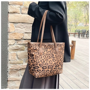 Detailed side view of a large leopard print tote bag styled with an elegant black blazer