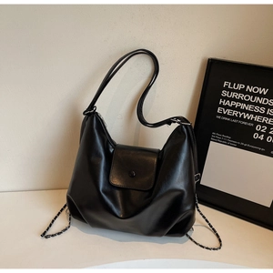 Detail of black semi-moon hobo bag with flap closure and woven chain decoration
