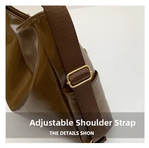 Detail view of adjustable shoulder strap with gold buckle on brown leather tote bag