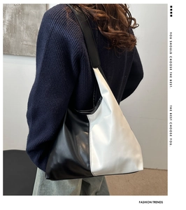 Detailed close-up of a large black and white contrast leather tote bag on a female model