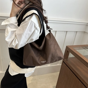 Retro brown faux suede shoulder bag with adjustable knot straps and metallic logo detail