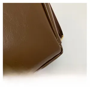 Close-up of premium glossy brown synthetic leather with natural cracked texture and stitching