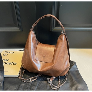 Close-up of brown vintage tote bag featuring faux leather texture and decorative chain