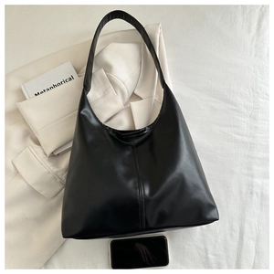 Close-up of black matte leather hobo bag featuring a vertical seam and wide shoulder strap